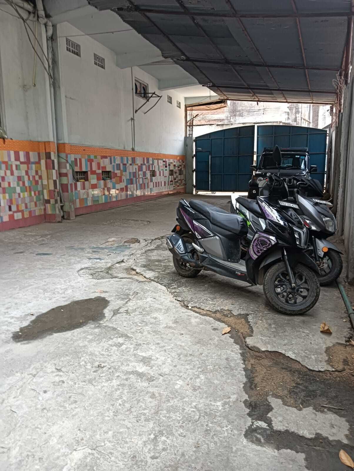 A motorcycle parked in a garage with a tiled wall and a blue garage door.