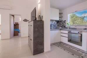 Una cocina moderna con gabinetes blancos, horno integrado y un amplio ventanal.