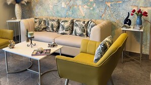 A living room with a sofa, two armchairs, a coffee table, a ceiling fan, and a decorative wall mural. - HOTEL BAHIA AZUL  (Cartagena)