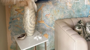 Une pièce avec un mur à texture, une table blanche ornée d’un vase décoratif et un canapé beige.