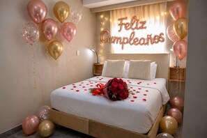 A bed with rose petals and a bouquet, surrounded by balloons and a 'Feliz Cumpleaños' sign. - HOTEL BAHIA AZUL  (Cartagena)
