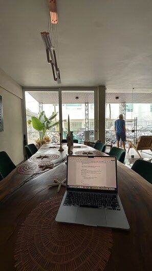 A wooden table with a laptop, a woven placemat, and a decorative vase. - HOTEL BAHIA AZUL  (Cartagena)