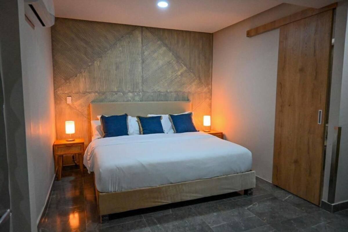 A bedroom with a bed, two bedside lamps, a wooden headboard, and a wardrobe.