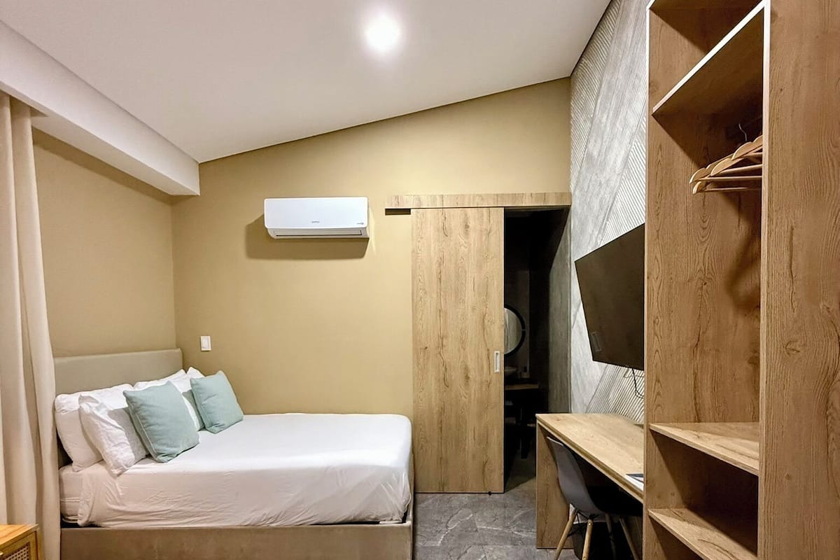A bedroom with a bed, a desk, and a wardrobe.