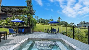 A pool area with a hot tub, blue chairs, and umbrellas.