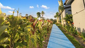 A pathway lined with tropical plants and a building with a modern design.