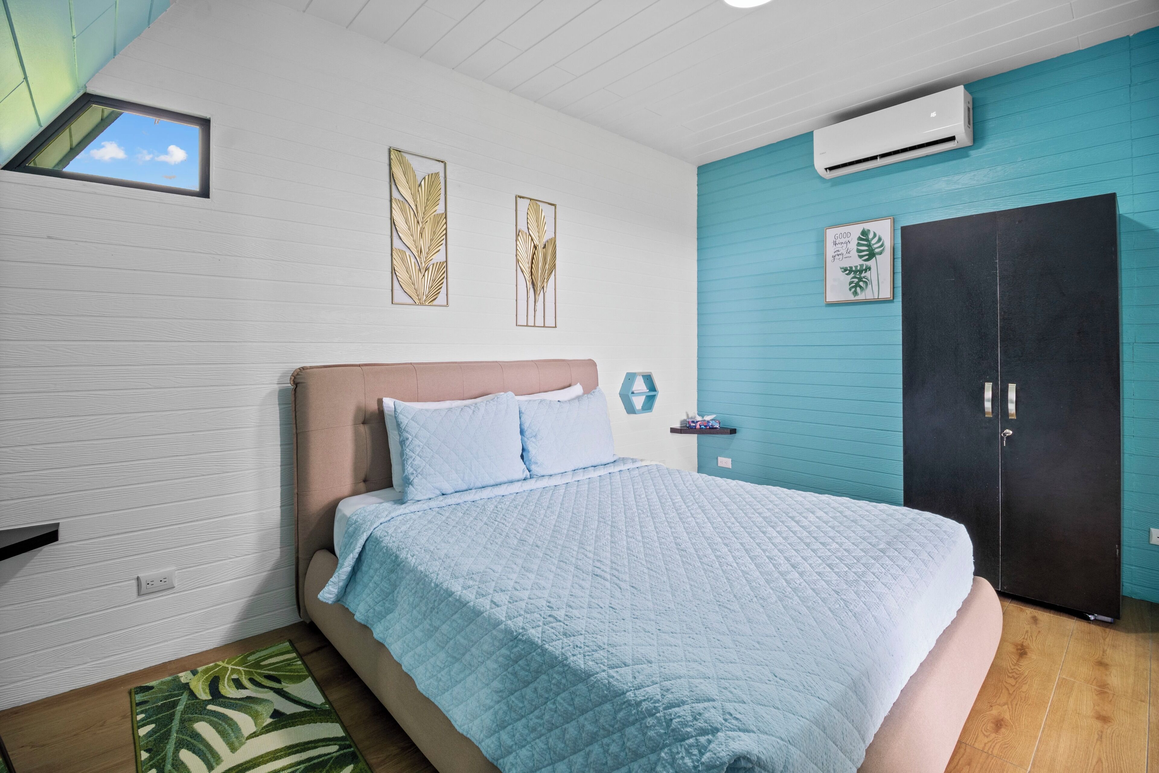 A bedroom with a bed, a wardrobe, a window, and wall decorations.