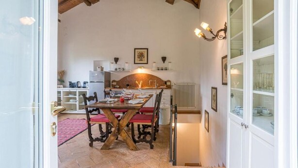 Una cocina rústica con una mesa de madera, sillas y una lámpara colgante.