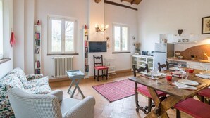 Una sala de estar acogedora con chimenea, una mesa de comedor para cuatro personas y una zona de cocina con refrigerador y estufa.