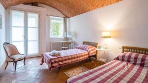 Una habitación con dos camas, una silla, una mesa, una lámpara y una ventana.
