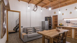 Une cuisine de taille modeste, avec une table et des chaises en bois, un canapé gris et un réfrigérateur.