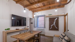 Une cuisine moderne avec une table en bois, des chaises, un grand téléviseur et une fenêtre donnant sur un beau paysage.
