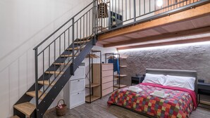 Une chambre à coucher avec un lit, un escalier en bois, un petit bureau et une armoire.