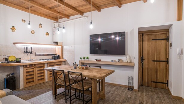 Une cuisine moderne avec des meubles en bois, une table à manger et des luminaires suspendus.