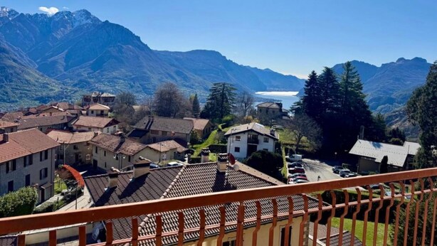 Paisaje montañoso con un pueblo, casas escalonadas y un lago.