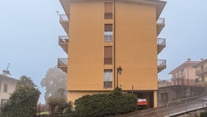 Un edificio de varios pisos con balcones, una escalera central y un pequeño jardín.