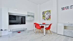 Una sala de estar moderna con un televisor de pantalla plana, sillas rojas y una obra de arte en la pared.