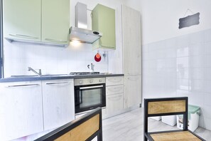 Uma cozinha moderna com armários brancos, fogão a gás, forno e coifa de aço inoxidável.