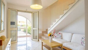 A modern interior with a sofa, a wooden table, a vase with flowers, and a staircase. - GuestHost - Villa Mirò - Escape to Salento (Melendugno)