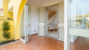 An open glass door leading to a room with a bed, a small table, and a staircase. - GuestHost - Villa Mirò - Escape to Salento (Melendugno)
