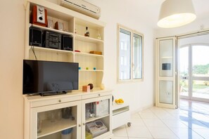 A modern living room with a flat-screen TV, built-in speakers, and a glass cabinet.
