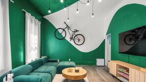 A modern living room with green walls, a large sofa, a wooden coffee table, and a television on a wooden stand. - Downtown Sustainable Garden House (Halifax)