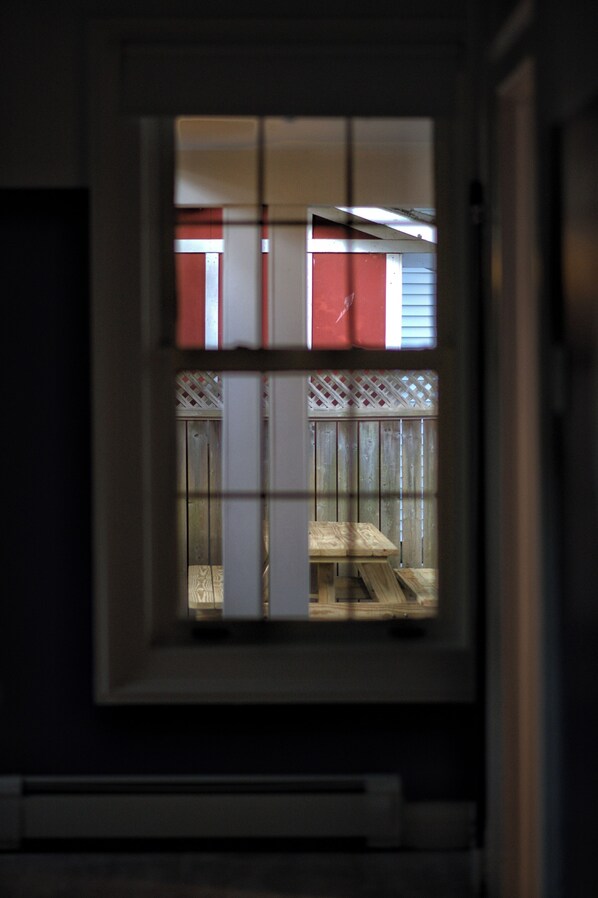 A view through a window with a grid pattern, leading to a room with a wooden floor and a white door. - Downtown Sustainable Garden House (Halifax)