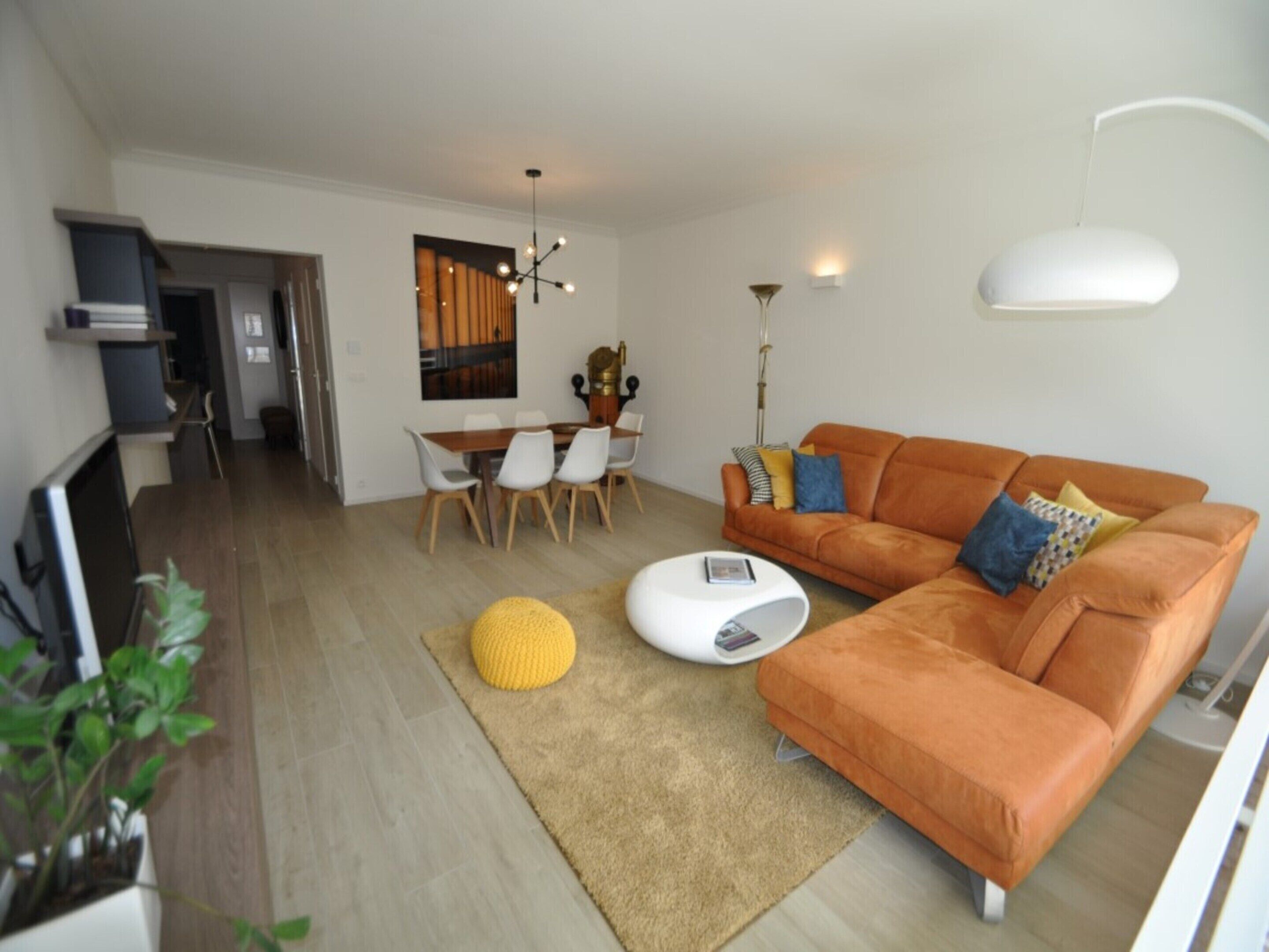 Ein modernes Wohnzimmer mit einer Couch, einem Couchtisch und einem Essbereich mit Stühlen und einem Tisch.
