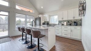 A modern kitchen with a large island, white cabinetry, and a view to the outside.