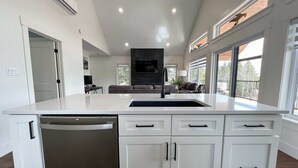 A modern kitchen with a central island, white cabinetry, and a built-in dishwasher.