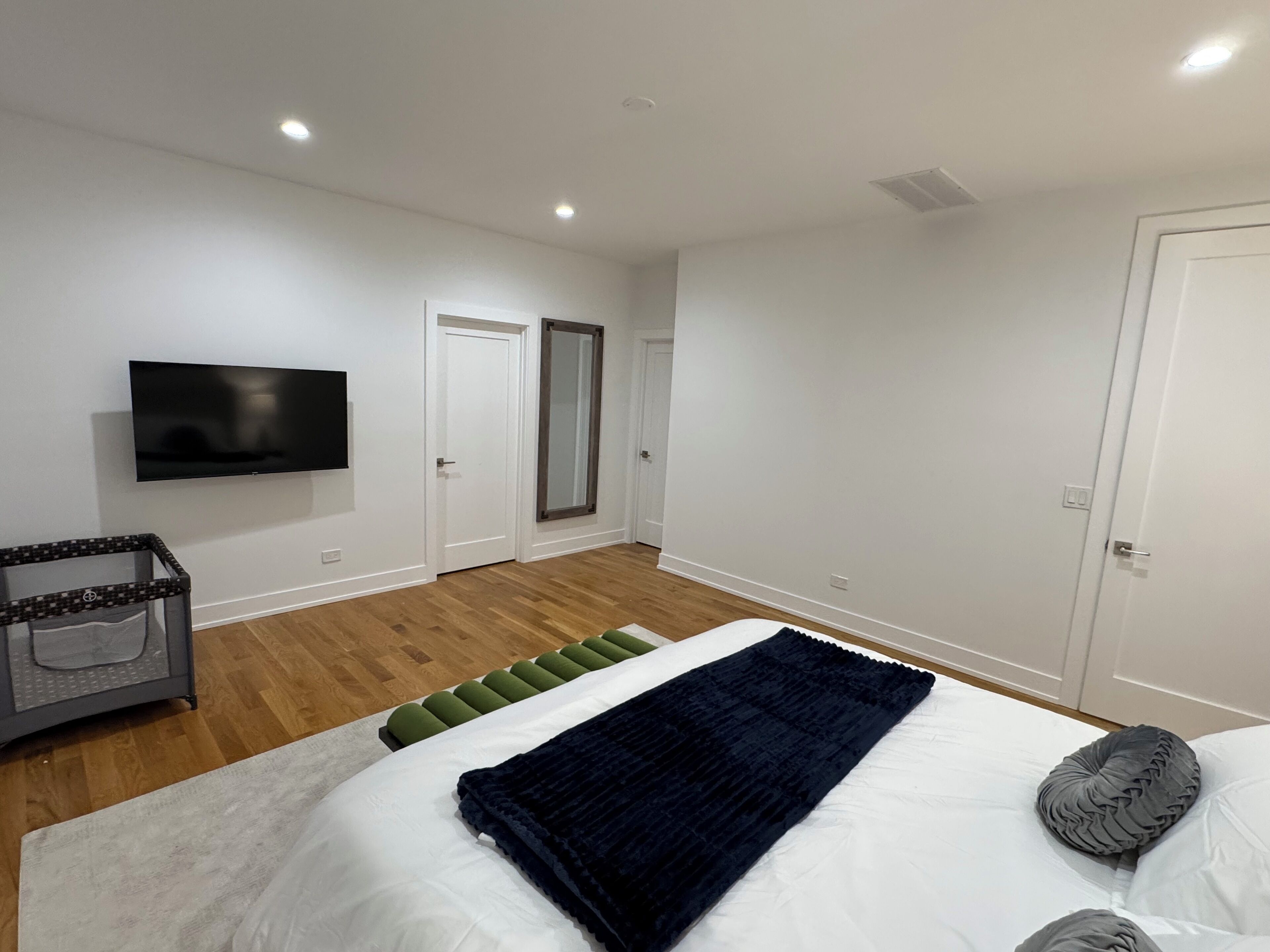 A modern bedroom with a bed, a flat-screen TV, a small table, and a mirror.