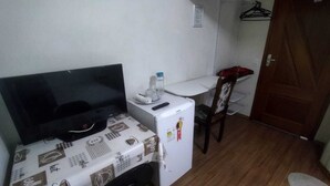 A small room with a TV, a refrigerator, a table, and a chair. - Azure Flats (Curitiba)