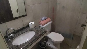 A bathroom with a sink, toilet, and a shower area. - Azure Flats (Curitiba)