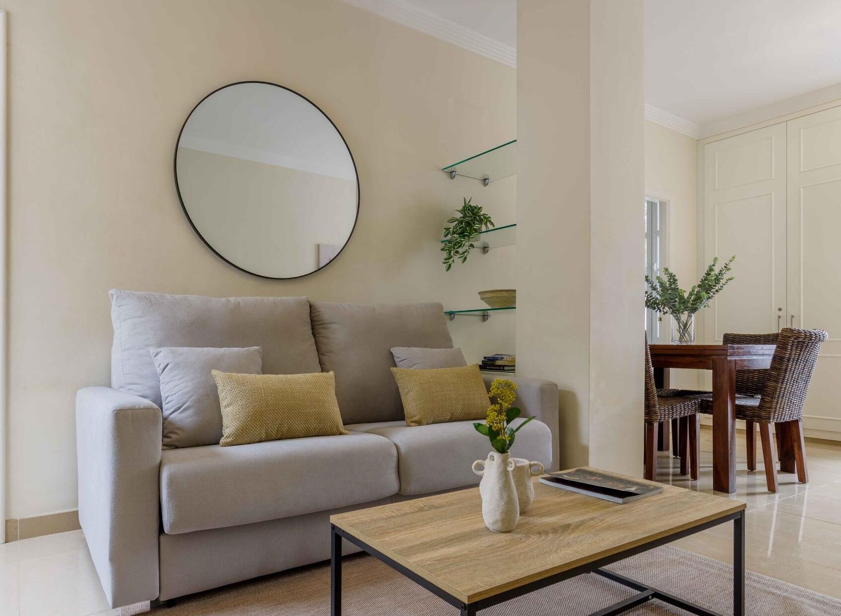 A living room with a sofa, coffee table, and a dining area with chairs and a table.