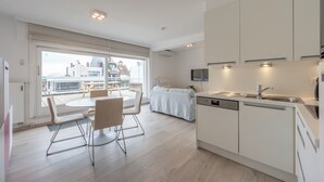 A modern kitchen with a dining area, large windows, and a view of buildings.