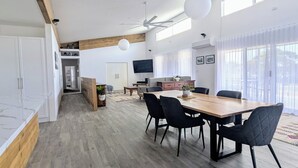 Una cocina moderna con armarios de madera, un comedor con mesa de madera y sillas negras, y un techo con diseño perforado.