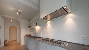 A modern kitchen with a central island, built-in gas stove, and under-cabinet lighting. - Villa in Knokke Near Alberstrand Beach (Knokke-Heist)
