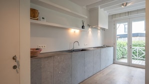 A modern kitchen with a built-in island, stainless steel appliances, and a large window providing natural light. - Villa in Knokke Near Alberstrand Beach (Knokke-Heist)