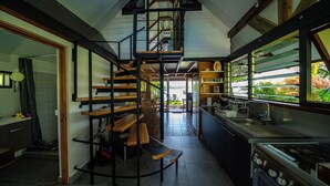 A compact kitchen with a central staircase, a built-in oven, and a view of the outdoors. - Toahere Beach House - Beachfront - Pool - Pontoon (Papeari)