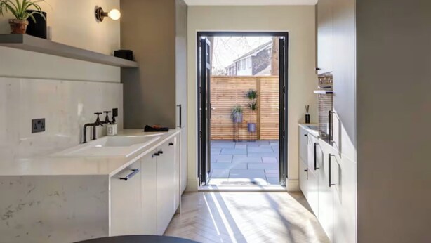 Una cocina moderna con armarios blancos, una encimera de mármol y un objeto circular negro en el suelo.