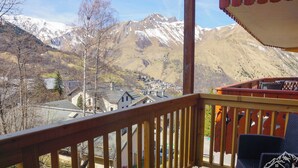 Un balcón de madera con vistas a una cadena montañosa y un pueblo en la falda.
