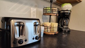 A kitchen counter with a Black & Decker toaster, a coffee maker, and a mug holder with cups.