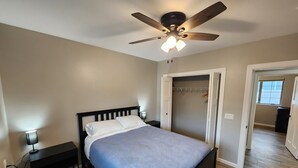 A bedroom with a bed, a nightstand, a ceiling fan, and a walk-in closet.
