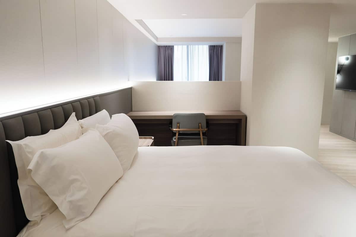 Une chambre d’hôtel moderne avec un grand lit, un bureau et une télévision.