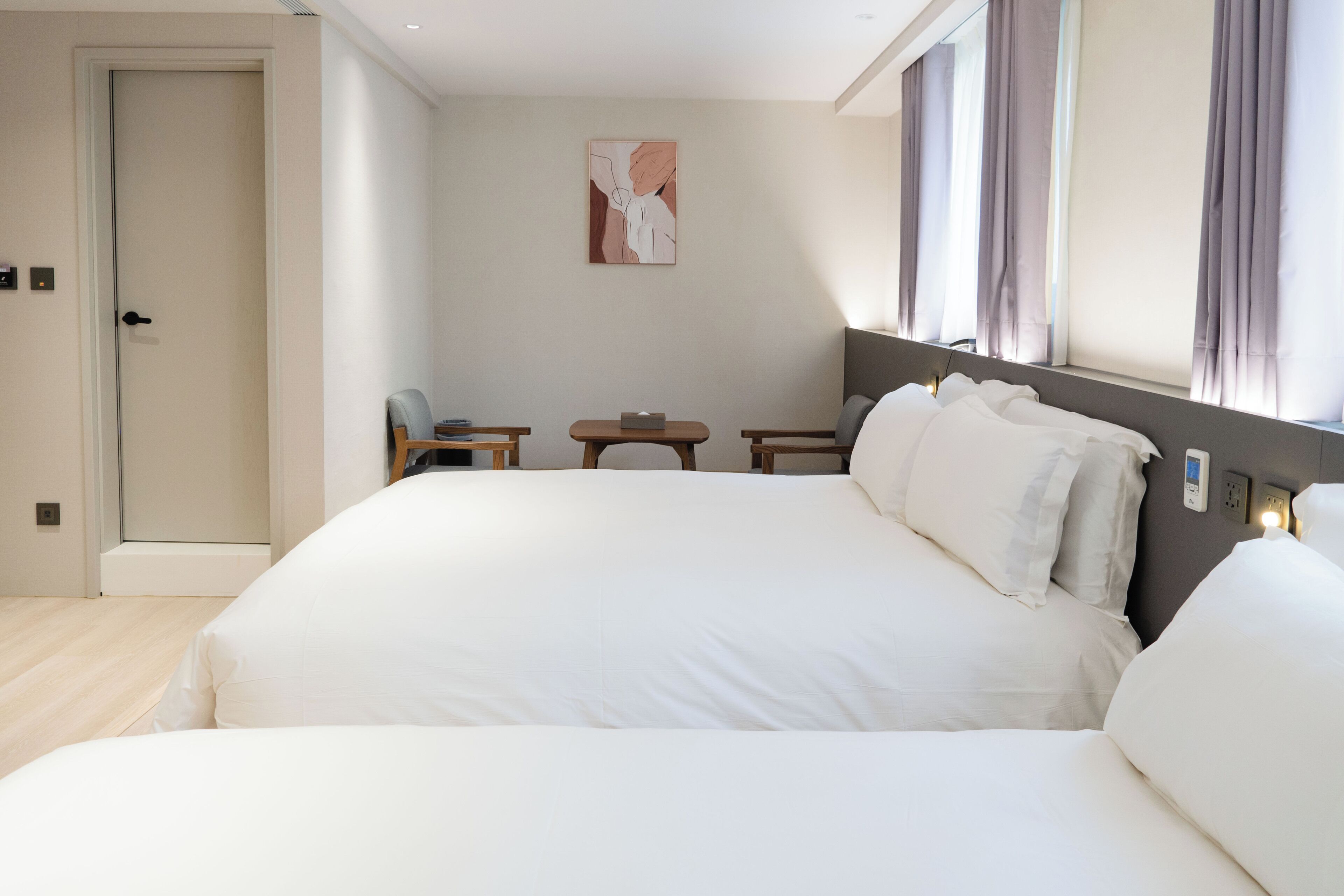 A hotel room with a large bed, bedside tables, a small table, and a painting on the wall.