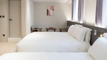 A hotel room with a large bed, bedside tables, a small table, and a painting on the wall.