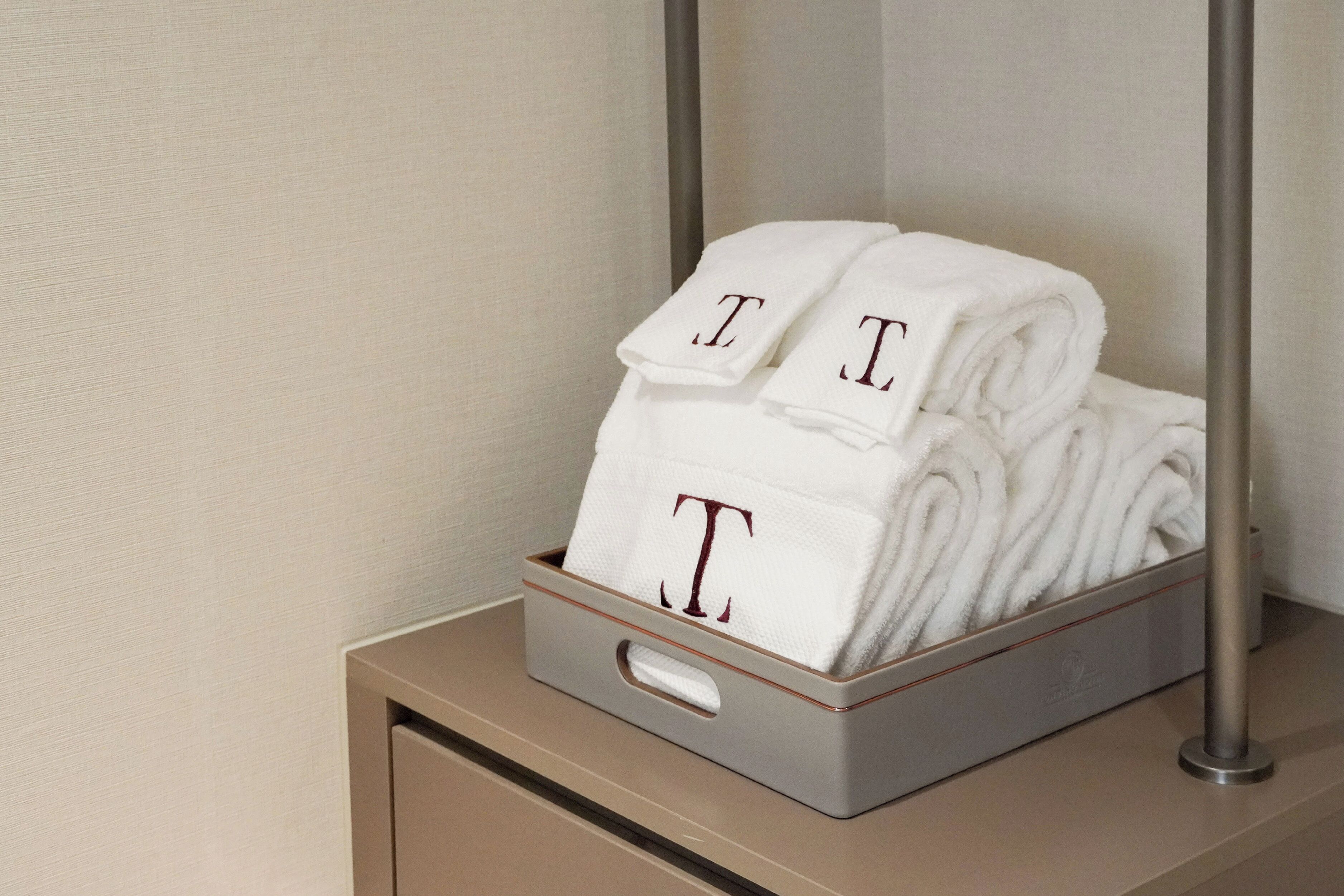A metal tray with folded white towels stacked on a wooden surface.