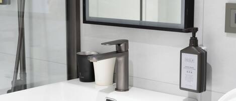 A modern bathroom with a white sink, a faucet, and a hand soap dispenser.