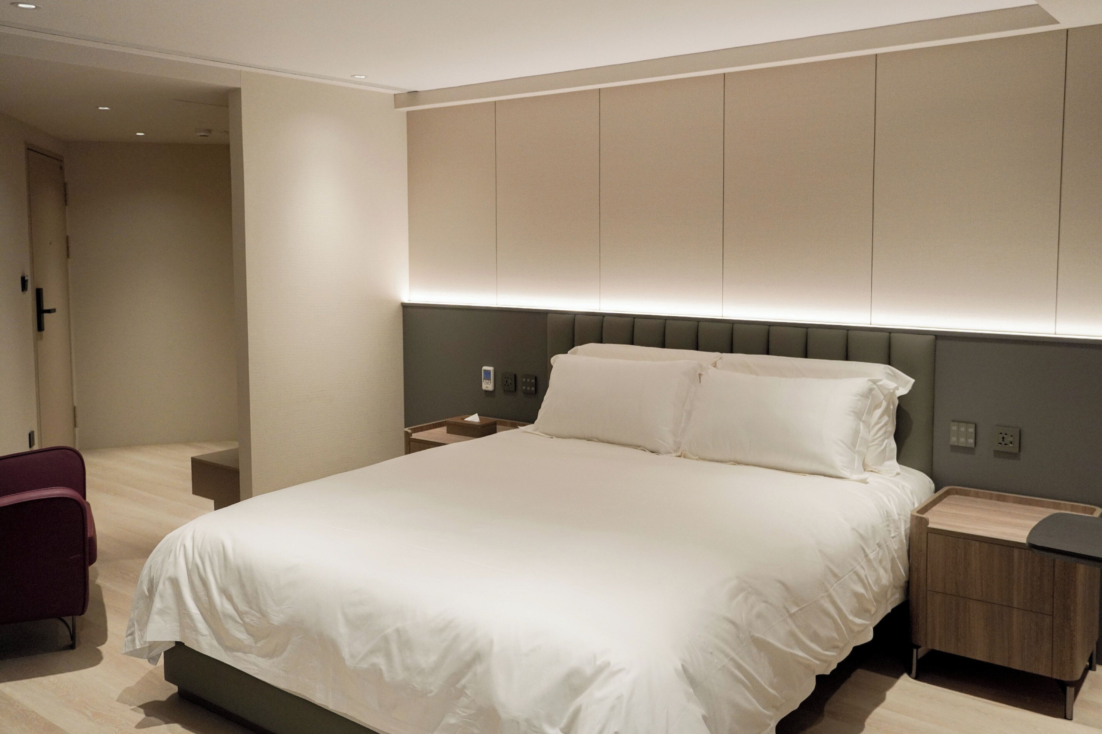 A modern hotel room with a large bed, bedside tables, and a chair.