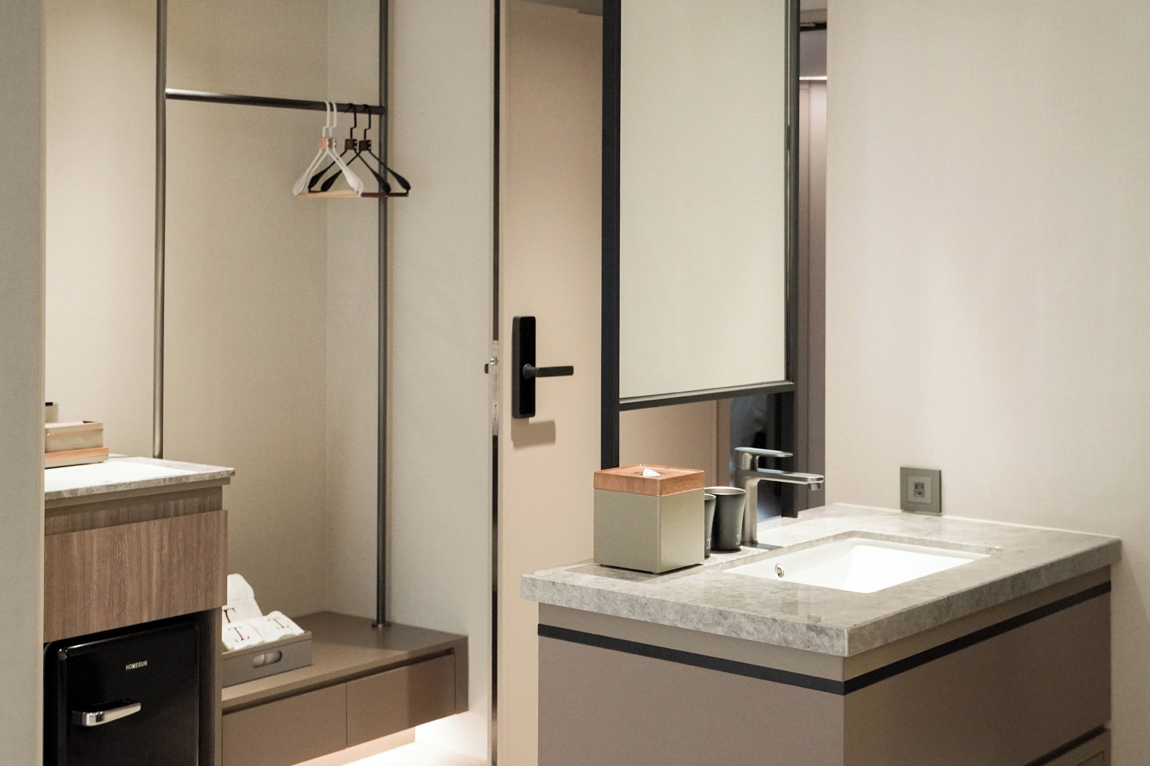 A modern bathroom with a large mirror, a sink, and a towel rack.